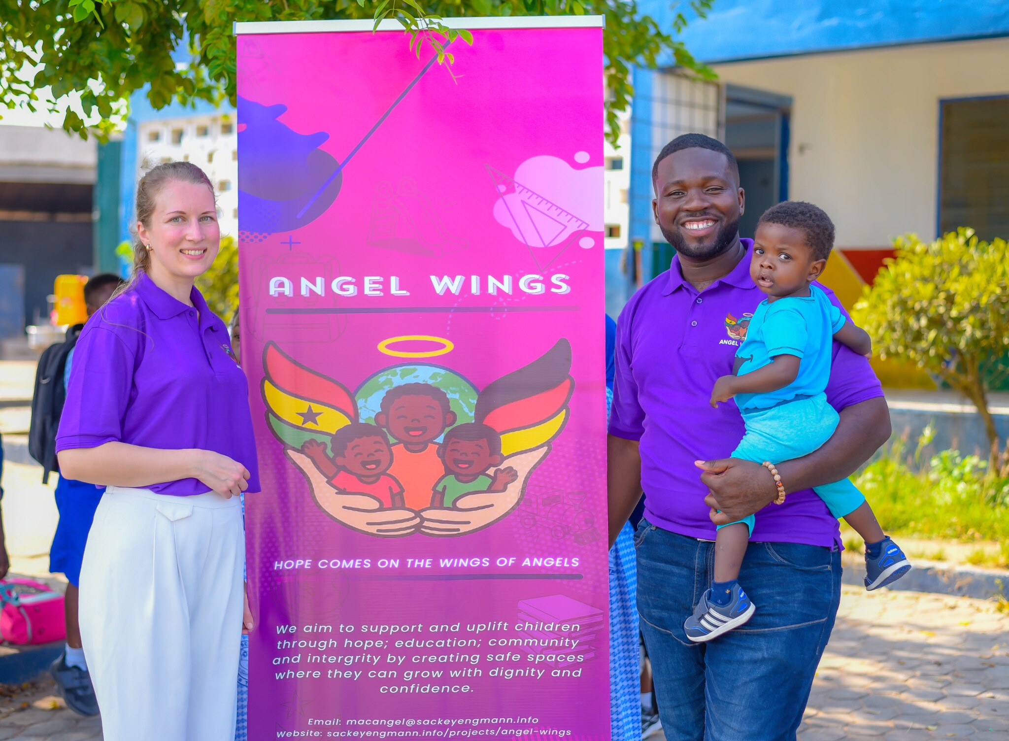 Eva Reischl, Mac Angel and a child beside the Angel Wings banner